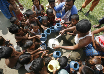 Flood-affected children crowd around a relief worker distributing free milk at a flood relief camp in Purniya in Bihar.
