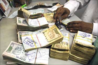 An employee arranges Indian currency notes at a cash counter in a bank.