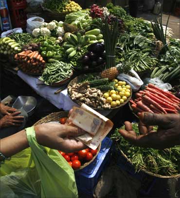 A customer pays money after buying vegetables from a street-side vendor in Mumbai.