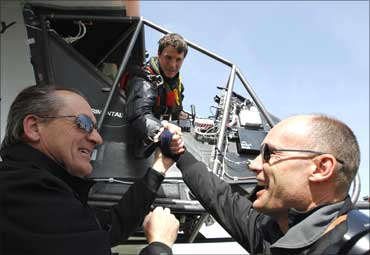 Bertrand Piccard (R), pilot and president of Solar Impulse and Andre Borschberg (L), CEO and pilot of the company, congratulate German test pilot Markus Scherdel.