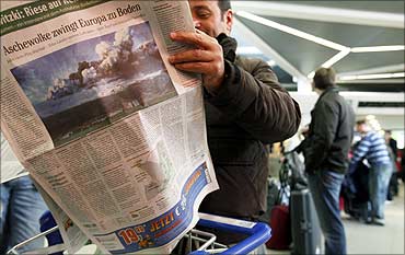 A stranded passenger reads a newspaper as he lines up at a ticket counter at Tegel airport in Berlin
