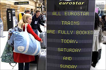 Passengers stand next to a Eurostar information sign at Gare du Nord station in Paris.