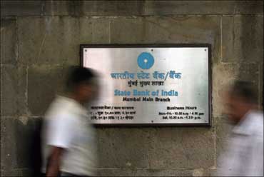 People walk past a State Bank of India board in Mumbai.
