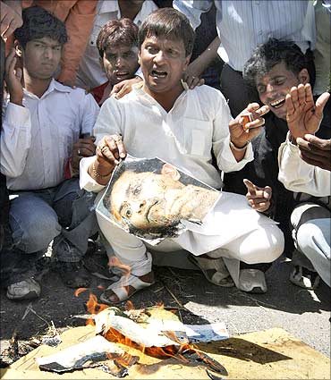 A protester holds a burning photograph of Lalit Modi.