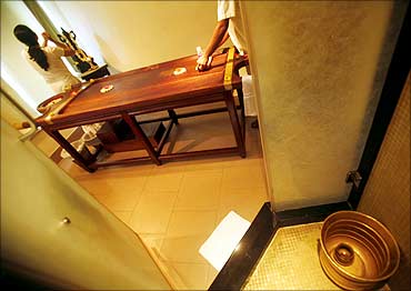 Therapists prepare a traditional Ayurvedic massage room for a customer.
