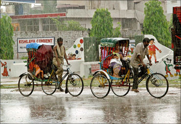 Rickshaw pullers taking passengers in driving rain in Mathura.