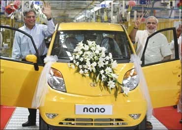 Ratan Tata (L), chairman of the Tata Group, and Gujarat's chief minister Narendra Modi wave as they stand beside the Tata Nano car during the inauguration ceremony of a new plant at Sanand.