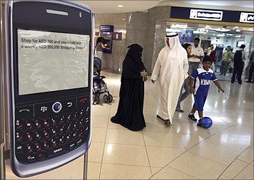 A family walks past a display of a BlackBerry smart phone at a shopping mall.