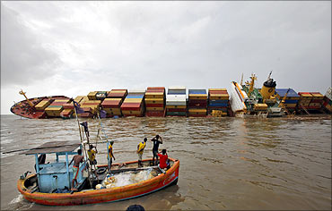 Fishermen take pictures of a damaged cargo ship MSC Chitra in the Arabian Sea off the Mumbai coast.