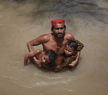 A man wades through flood waters towards a naval boat while evacuating his children in Sukkur, located in Pakistan's Sindh province.
