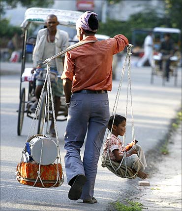 A street performer carries a child in a basket after performing a street show at Noida.