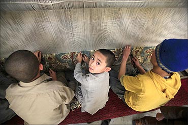 Mohammad Hussain (C), an Afghan boy, weaves carpets with his siblings in Peshawar.