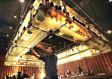 A bartender reaches out for a bottle at a bar in a luxury hotel in Mumbai.