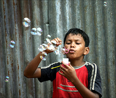 A boy selling bubble-making toys, blows bubbles to attract buyers in Mumbai.