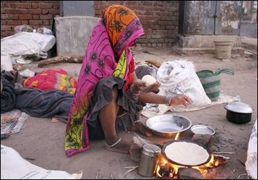 A homeless woman prepares food on a roadside in Ahmedabad.