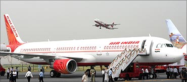 An Air India Airbus A321 sits on the tarmac as a Kingfisher Airlines aircraft takes off.