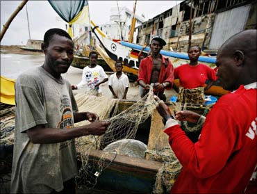 Local fishermen mend their nets in front of Cape Coast Castle, a former slave holding facility, in the Ghanaian town of Cape Coast.