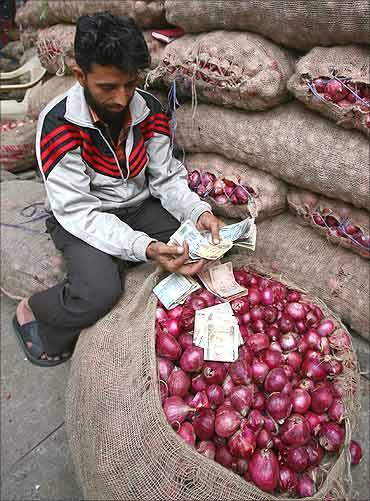 A vendor counts cash on a sack of onions at a vegetable wholesale market in Chandigarh.