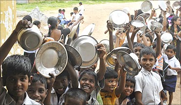 School children hold their plates as they wait for their free lunch at a government primary school.
