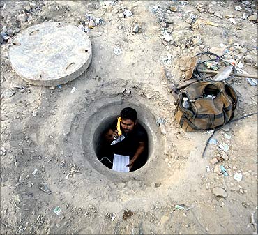 Munna Yadav, 35, speaks on a phone after repairing underground telephone cables at Noida.