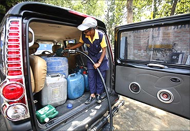 An employee fills up containers with petrol at a pump station.