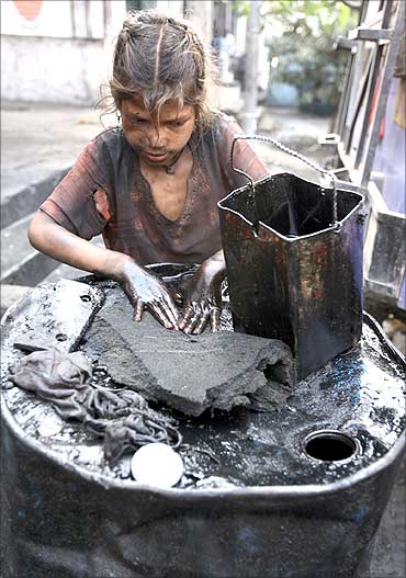 Gudia, an oil scavenger, collects engine oil at an auto workshop in Jammu.
