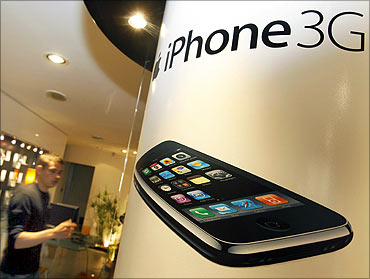 An advertisement for the Apple iPhone is shown at a retail store.