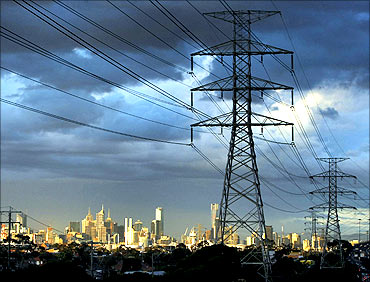 High voltage electrical transmission towers are seen near a freeway in Melbourne.