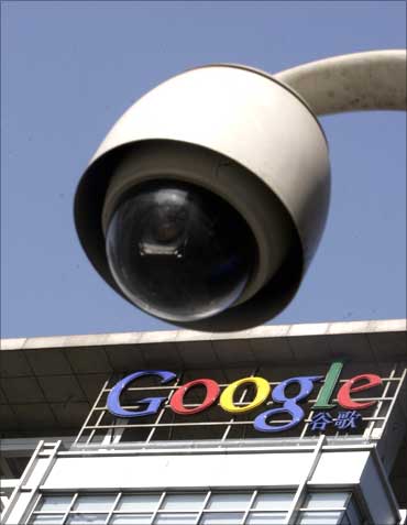 Google logo is seen on the top of its China headquarters building behind a road surveillance camera.