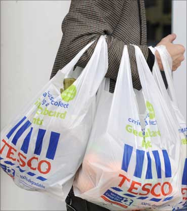 A shopper carries Tesco bags outside a branch of the supermarket, in west London.