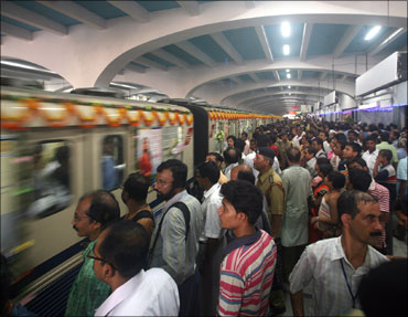 Passengers stand on a platform at a metro station in Kolkata.