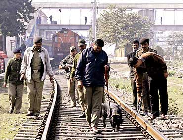 Security personnel with a sniffer dog inspect railway tracks.