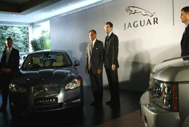 Tata Motors chairman Ratan Tata (L) and David Smith, CEO of Jaguar Land Rover, pose with a Jaguar XF and Range Rover Vogue SE.