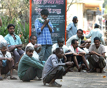 Daily wage workers wait for employment on a street side at an industrial area in Mumbai.