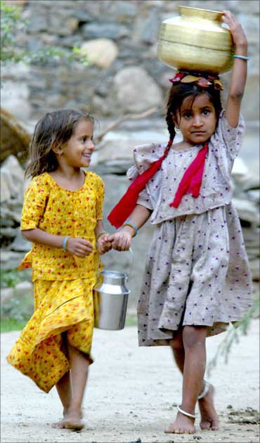Two village girls carry home water.