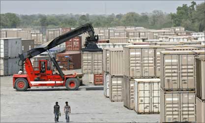 Workers walk beside the stacked containers at Sanand.