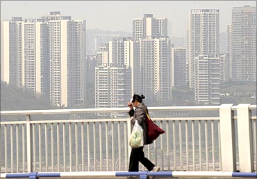 A pedestrian walks on a bridge as residential blocks are seen in the background in Chongqing.