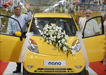 Ratan Tata (L), chairman of the Tata Group, and Gujarat's chief minister Narendra Modi wave as they stand beside the Tata Nano car during the inauguration ceremony of a new plant at Sanand.