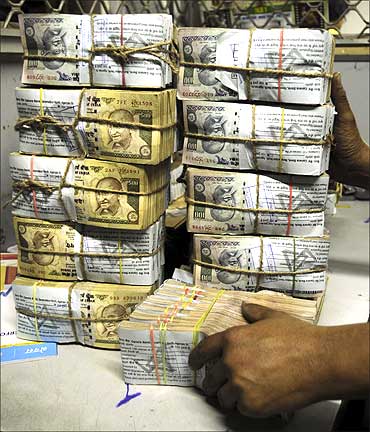 An employee counts bundles of Indian currency notes inside a bank in Agartala.
