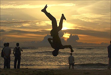 A boy somersaults on a beach against the backdrop of monsoon clouds in Kochi.