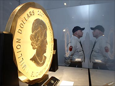 A security guard is reflected as he watches over the world's largest gold coin.