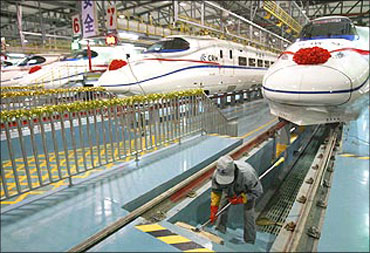 A labourer cleans the stairs beside a China Railway High-speed (CRH) train.