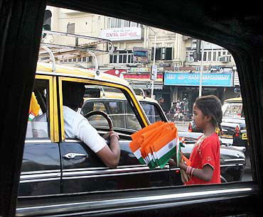 A girl sells flags at a traffic signal.