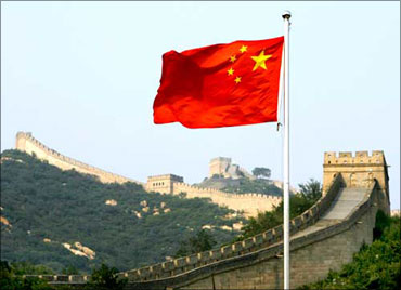 A Chinese flag flutters against the backdrop of the Great Wall of China.