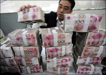 A Chinese bank employee placing currency notes on the bank counter.