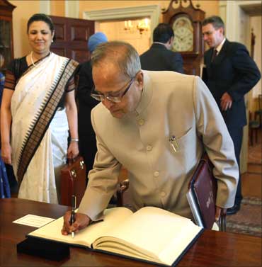 Finance Minister Pranab Mukherjee sigs the visitors book at the US State department, as Ambassador Meera Shankar looks on.