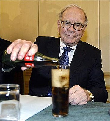 Warren Buffett fills a glass with Coke during a news conference in Madrid.