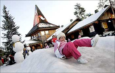A child slides on snow in front of the Santa Claus' Office in Santa Claus' Village.