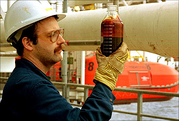 An oil rig worker checks a sample of the first crude oil to come out of Hibernia offshore resovoir.