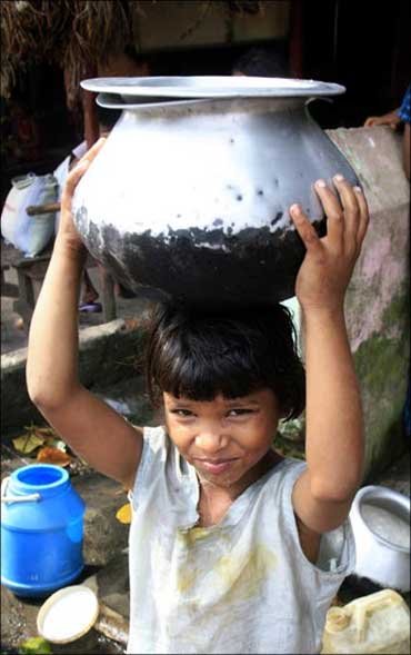 A homeless girl carries a pot of water in Kolkata.